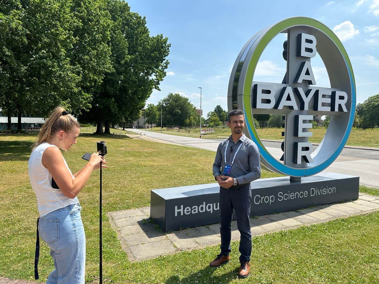 DynamoBot-Teammitglied wird neben dem Schild des Bayer-Crop-Science-Hauptsitzes gefilmt.