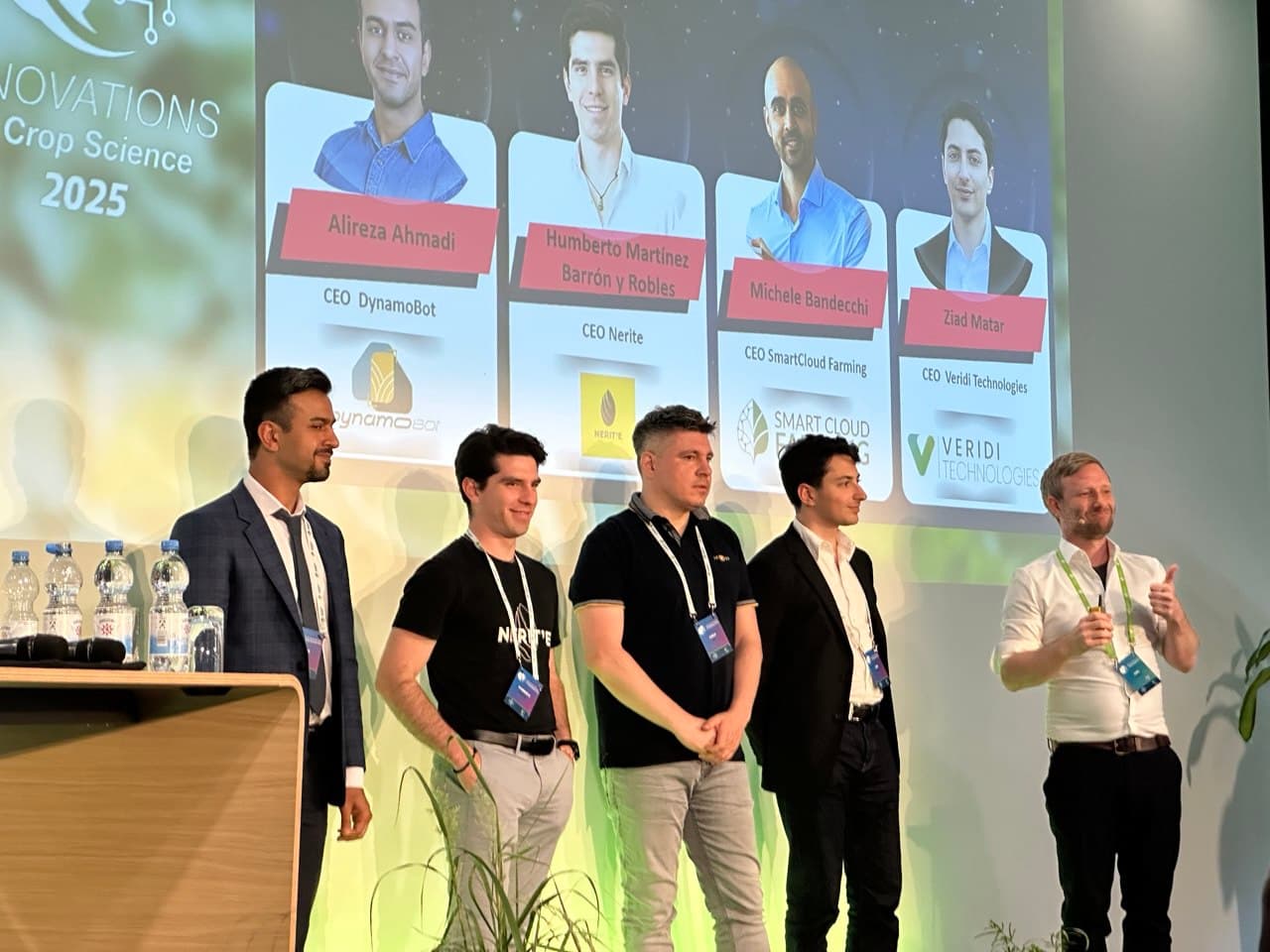 Fünf Gründer auf der Bühne einer Crop-Science-2025-Innovationsveranstaltung, DynamoBot-CEO Alireza Ahmadi auf dem Bildschirm genannt.